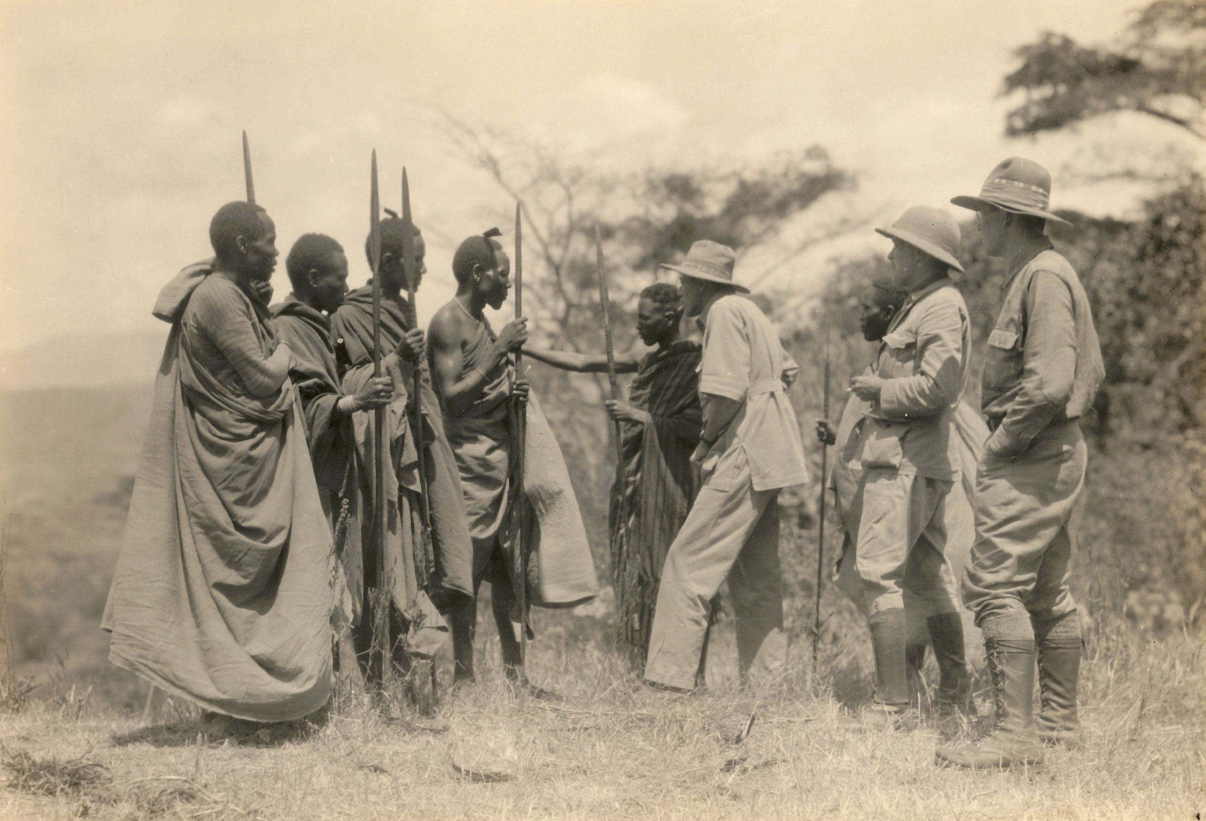 A group of Maasai warriors talk with safari hunters. 