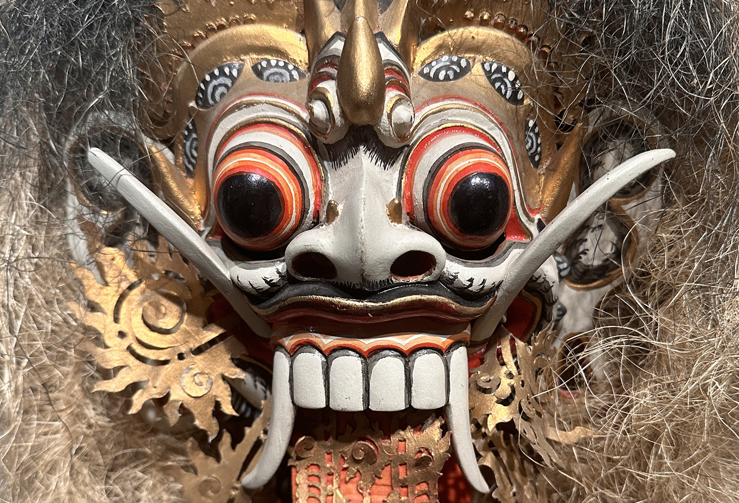 A closeup image of a mask of Rangda, showing the bulging eyes and teeth.
